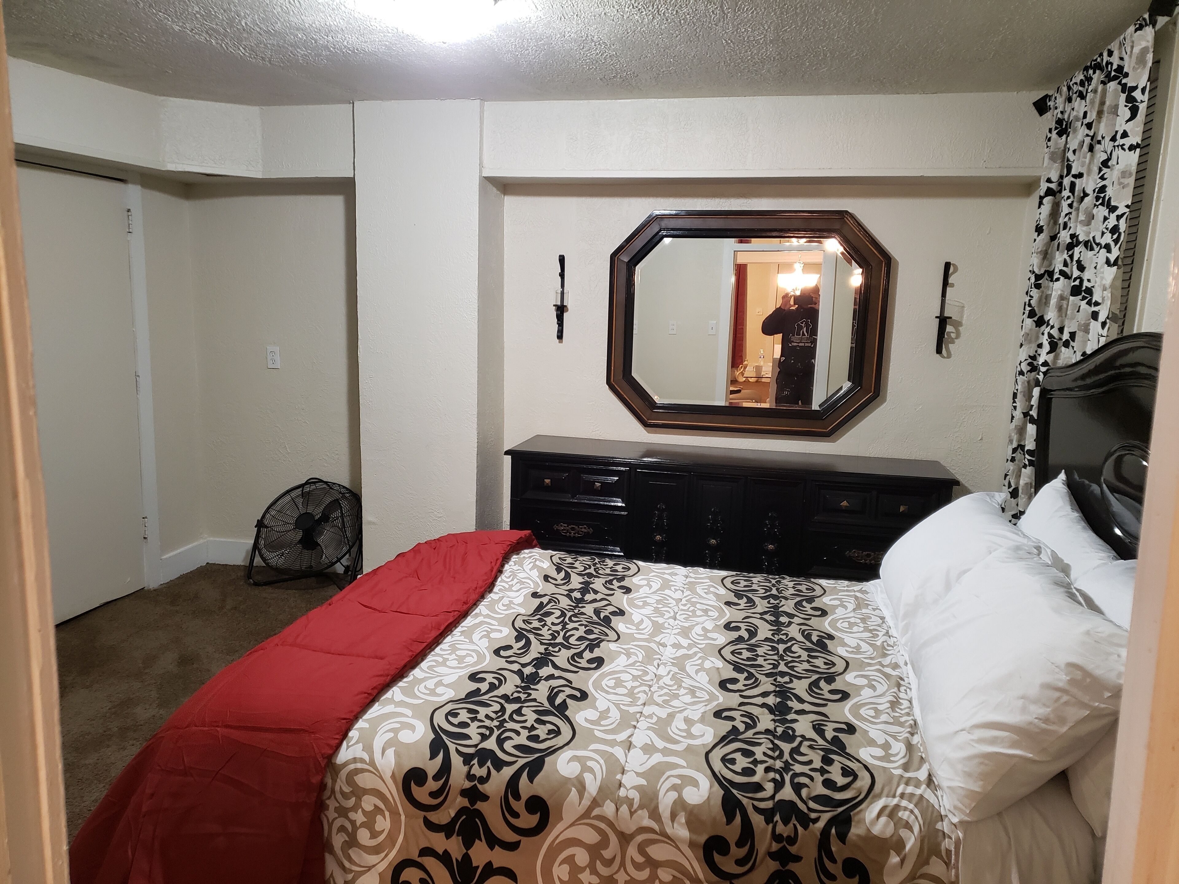A bedroom with a bed, dresser, and a mirror on the wall.