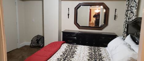 A bedroom with a bed, dresser, and a mirror on the wall.