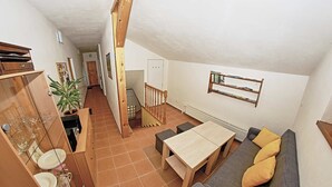 A compact living space with a dining table, sofa, and a staircase leading to another room. - VILA RHEA - Ubytovanie Vysoke Tatry (Vazec)