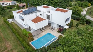 Ein modernes, zweistöckiges Haus mit Swimmingpool, Solaranlage und einem gepflegten Garten.