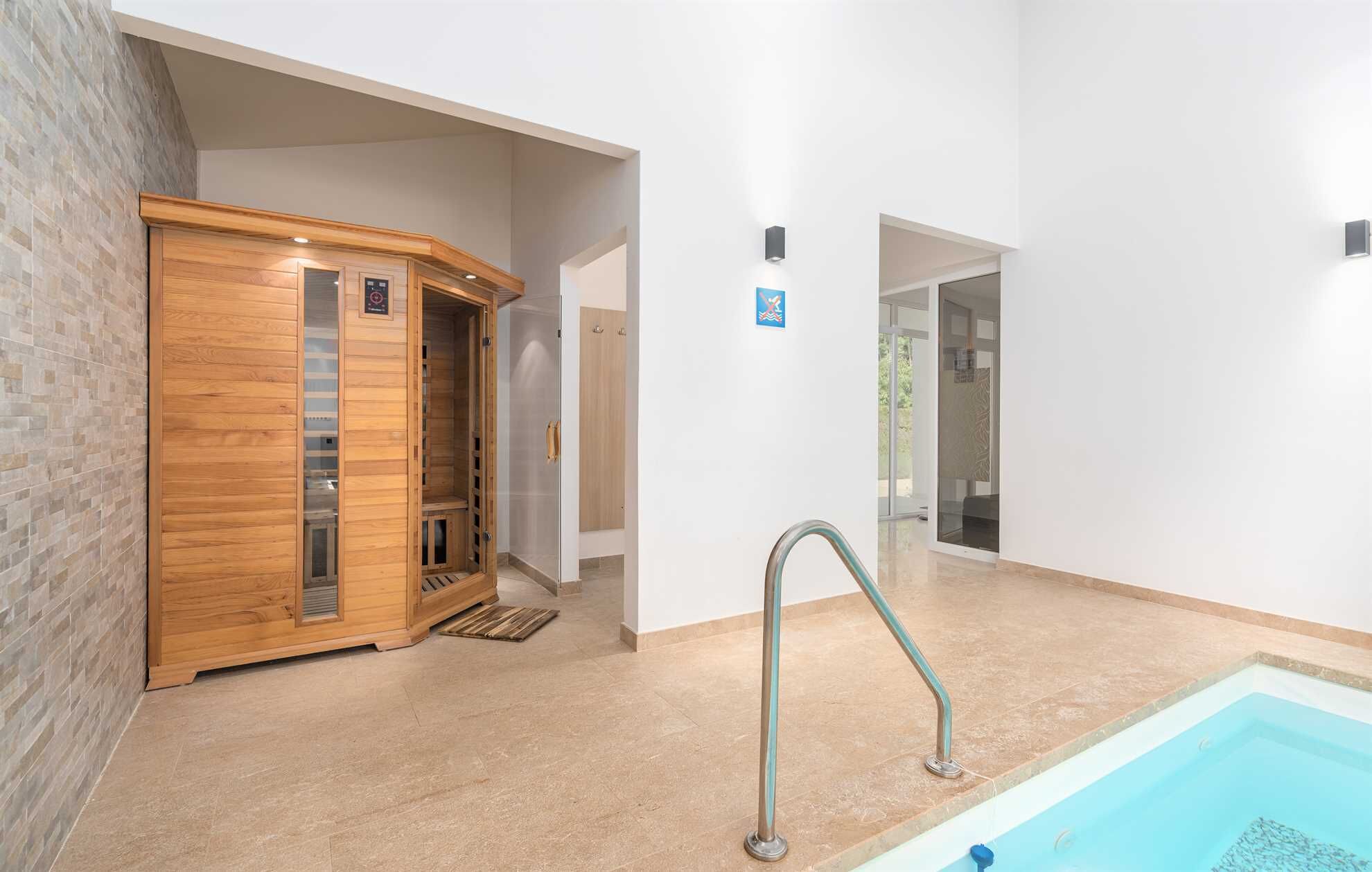 Ein moderner Wellnessbereich mit Holzzimmer, einer gläsernen Dusche und einem Pool.