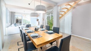 Ein moderner Essbereich mit einem Holztisch, gedeckt für vier Personen, schwarzen Stühlen und Pendelleuchten.
