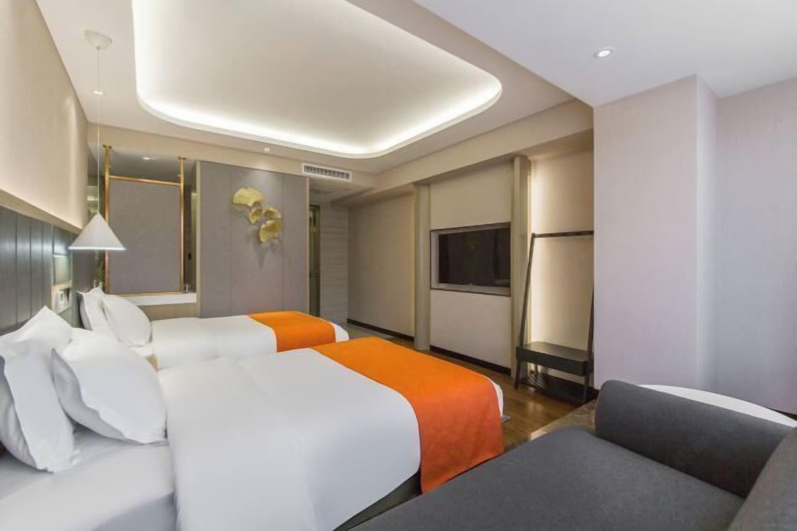 Une chambre d’hôtel avec deux lits, une télévision et un canapé.