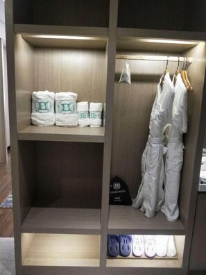 A hotel room with a wooden wardrobe containing towels, a black bag, and a pair of white pants. - Huaxi Hongta Avenue High-speed Railway Station (Yuxi)