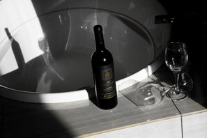 A bottle of wine and a wine glass on a reflective surface.