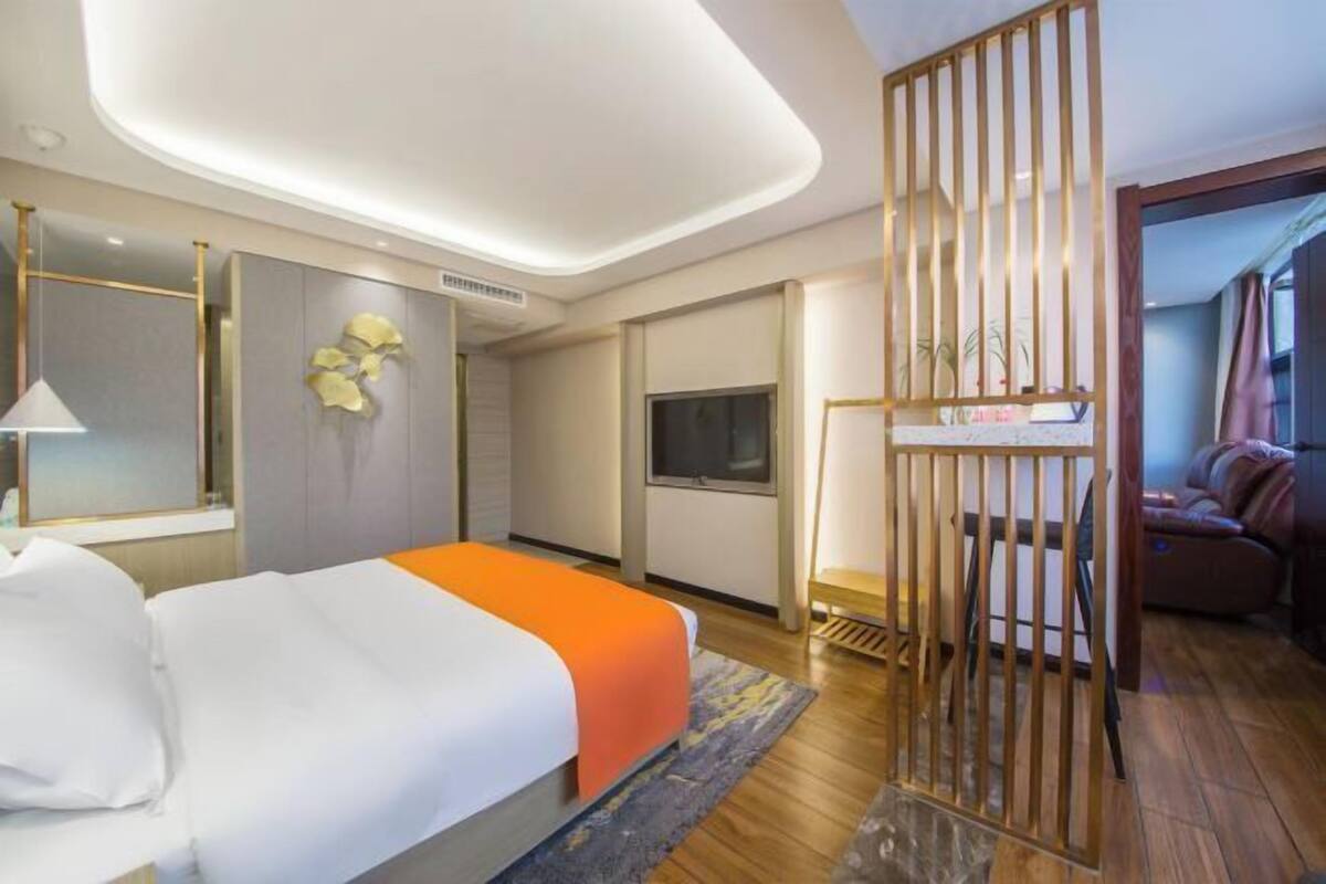 A modern hotel room with a bed, a desk, a TV, and a balcony.