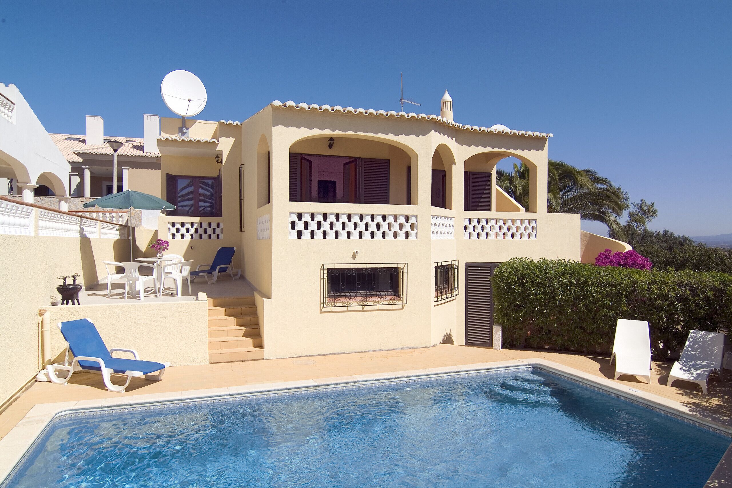Un bâtiment à deux étages doté d’une piscine, d’un espace extérieur aménagé et d’une antenne parabolique.