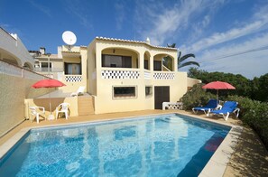 A poolside area with a swimming pool, lounge chairs, and umbrellas.