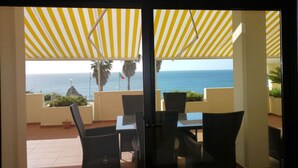 A balcony with a view of the sea, featuring a table and chairs under a striped awning. - Casa Aurora with sea view and beautiful terrace, Iberlagos Resort (Lagos)