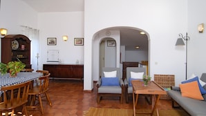 A spacious living area with a dining table, chairs, a sofa, and a kitchen in the background. - Casa Alma Mar, 2 minutes' walk to the beach (Luz)