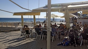 A beachside café with outdoor seating and umbrellas, overlooking the sea. - Casa Alma Mar, 2 minutes' walk to the beach (Luz)