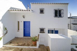 A white building with a blue door, a small window, and a potted plant. - Casa Alma Mar, 2 minutes' walk to the beach (Luz)