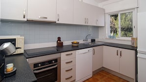 A modern kitchen with white cabinets, a black countertop, and a window with a view of greenery. - Casa Alma Mar, 2 minutes' walk to the beach (Luz)