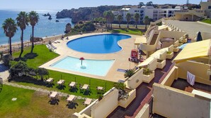 A resort with a large swimming pool, palm trees, and a view of the sea. - Casa Sara, Iberlagos Resort, breathtaking sea view (Lagos)