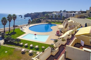 A resort with a large swimming pool, palm trees, and a view of the sea. - Casa Sara, Iberlagos Resort, breathtaking sea view (Lagos)