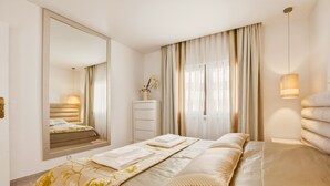 A modern bedroom with a large bed, a dresser, a mirror, and a window with curtains. - Casa Sara, Iberlagos Resort, breathtaking sea view (Lagos)
