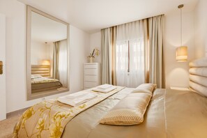 A modern bedroom with a large bed, a dresser, a mirror, and a window with curtains. - Casa Sara, Iberlagos Resort, breathtaking sea view (Lagos)