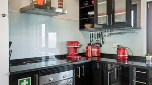 A modern kitchen with black cabinets, a stainless steel range hood, and a red coffee maker. - Casa Sara, Iberlagos Resort, breathtaking sea view (Lagos)