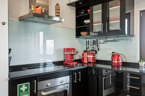 A modern kitchen with black cabinets, a stainless steel range hood, and a red coffee maker. - Casa Sara, Iberlagos Resort, breathtaking sea view (Lagos)