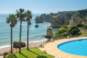 A pool area with a view of the ocean and cliffs.
