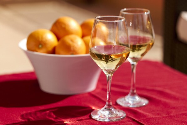 Two wine glasses on a red tablecloth with a bowl of oranges in the background. - Quinta Marina with sea views, private pool and garden (Lagos)
