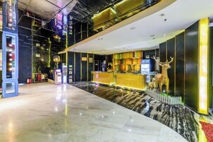 Un vestíbulo de hotel con una recepción, una zona de bar y una estatua decorativa de un ciervo.