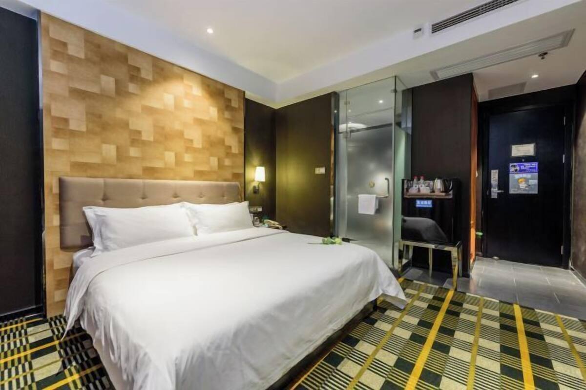 Une chambre d’hôtel avec un lit, un miroir, une douche et une petite table avec des articles de toilette.