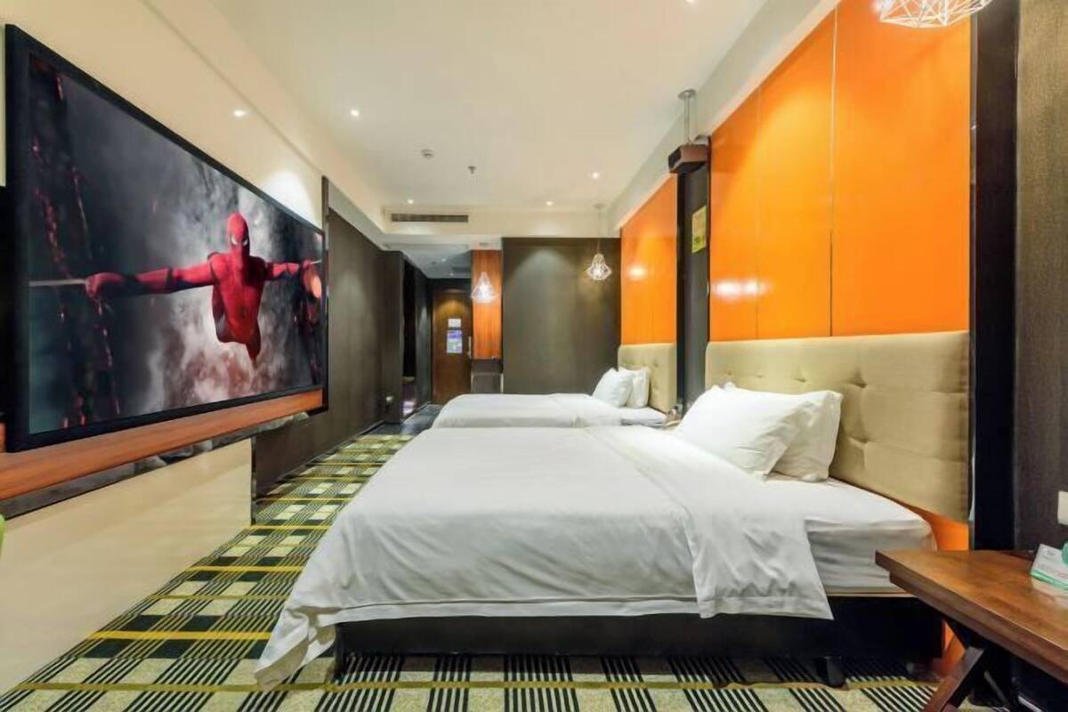 Une chambre d’hôtel avec deux lits, un grand téléviseur fixé au mur et un sol à motifs.