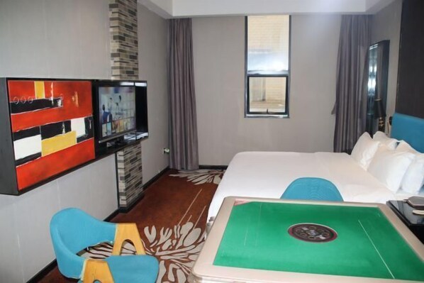 A hotel room with a bed, a TV, a desk, and a green table. - Huanyu Hotel (Lingshan Bus Terminal) (Lingshan)