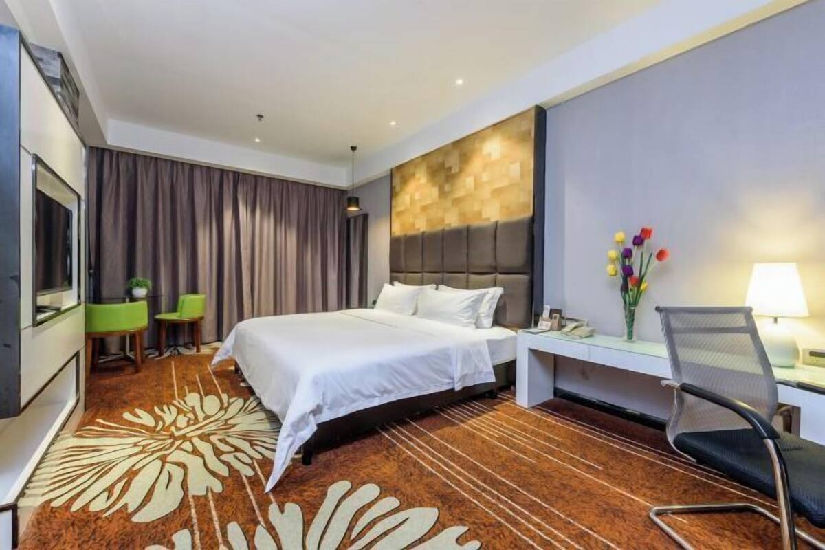 Une chambre d’hôtel avec un lit, un bureau, une chaise, une télévision et une grande fenêtre.