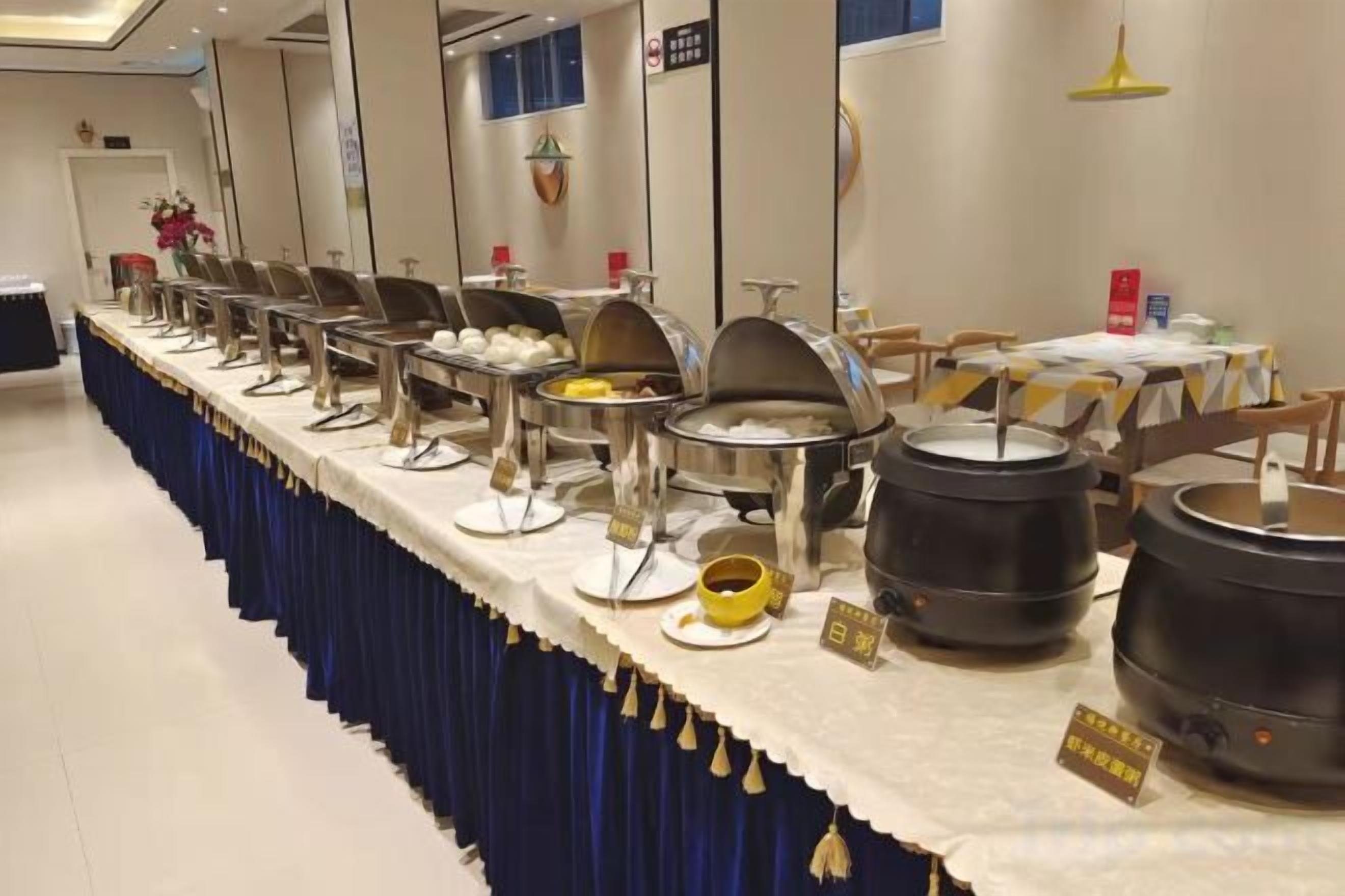 A buffet setup with multiple serving stations and a long table covered with a blue tablecloth.