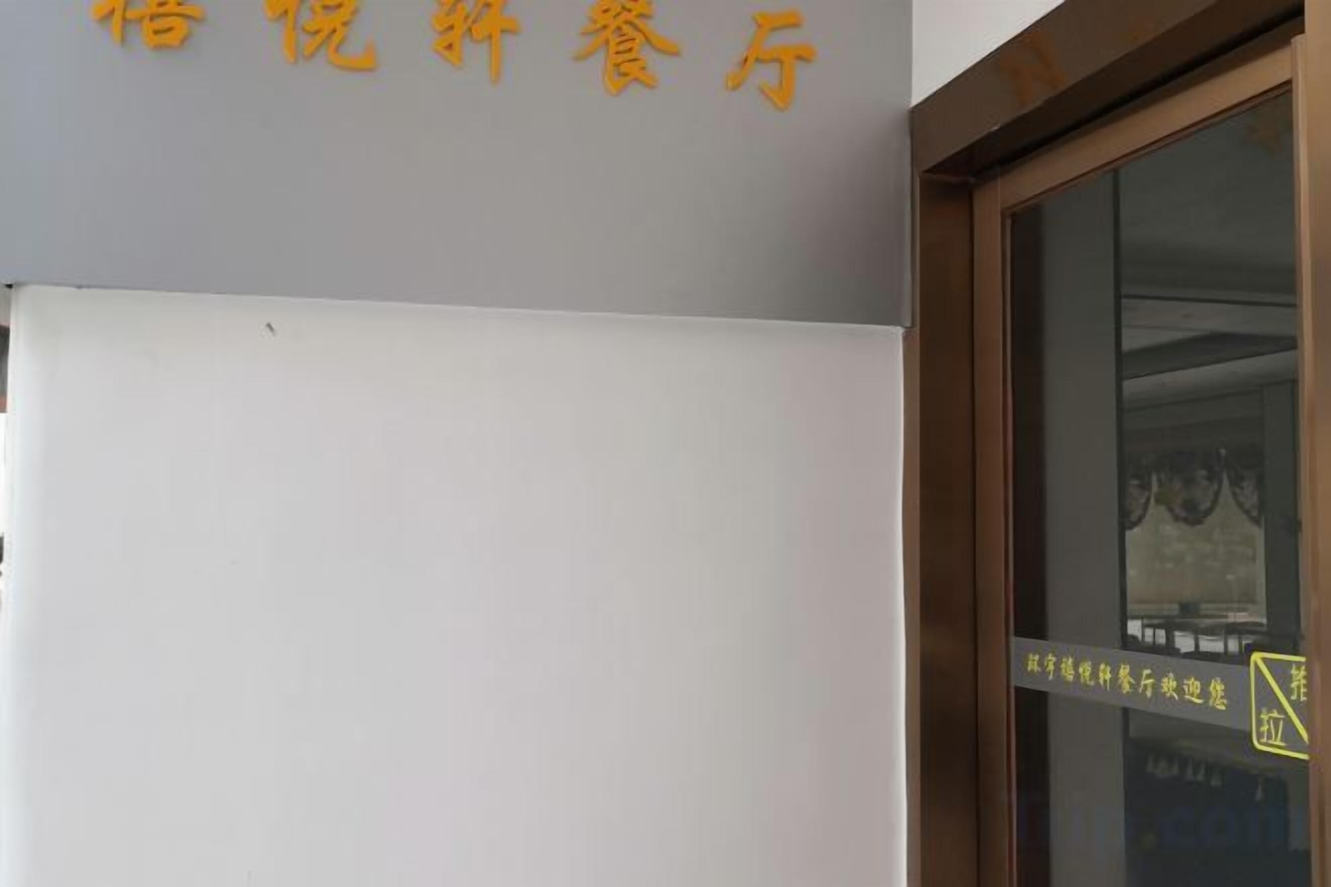 A hotel sign with Chinese characters and a window with a reflection.