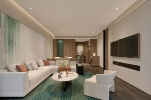 Una sala de estar moderna con un sofá modular, una mesa de centro redonda y un televisor montado en la pared.