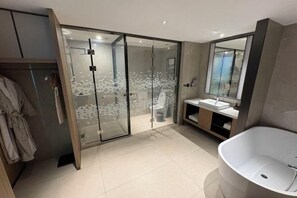 A modern bathroom with a freestanding bathtub, a glass shower enclosure, and a vanity with a mirror. - Jindu Hotel (Gucheng)