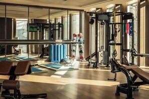 Une salle de sport équipée de matériel d’exercice, de tapis et d’un mur recouvert de miroirs.