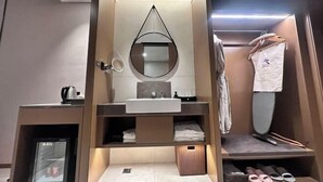 A modern bathroom with a sink, mirror, and storage shelves. - Jindu Hotel (Gucheng)