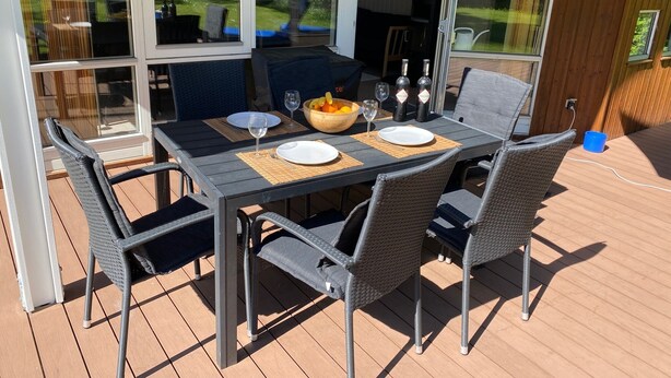 An outdoor dining area with a table set for four, surrounded by wicker chairs. - Smidstrup Strand 4-bed Summer Cottage, Sleeps 8 (Gilleleje)