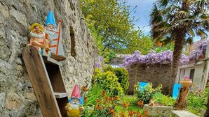 Een rustieke tuin met stenen muren, houten constructies en levendige bloemen.