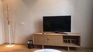 Un salon moderne avec un téléviseur à écran plat posé sur un meuble TV en bois, une lampe sur pied et deux petites tables basses rondes en marbre.