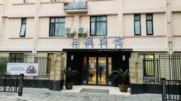 A hotel entrance with a signboard, a gated entrance, and potted plants.