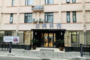 A hotel entrance with a signboard, a gated entrance, and potted plants. - Shanghai Sanhang Hotel (Shanghai)