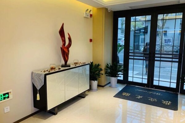 A reception area with a white console, a red abstract sculpture, and a potted plant.