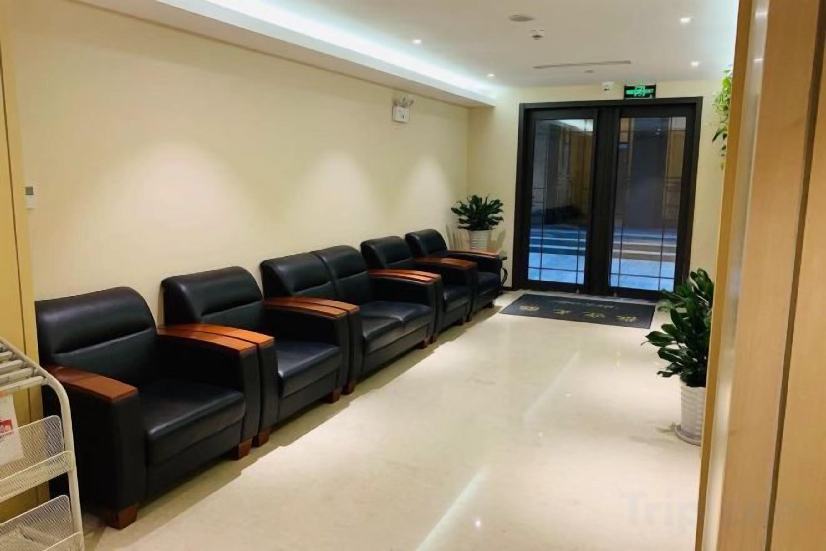 Un área de recepción con una fila de sillones de cuero negro y un mostrador blanco.