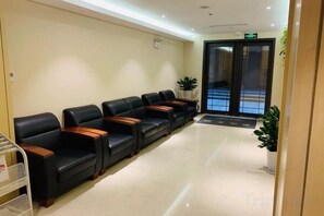 A reception area with a row of black leather chairs and a white reception desk. - Shanghai Sanhang Hotel (Shanghai)