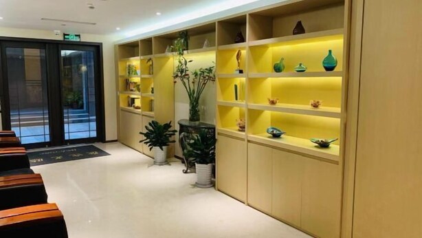 Un hall d’hôtel comprenant un comptoir d’accueil, un espace salon et des étagères ornées d’objets décoratifs.