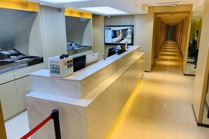 A hotel reception area with a marble counter, a red rope barrier, and a corridor leading to another section. - Shanghai Sanhang Hotel (Shanghai)