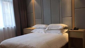 Un lit bien fait, avec du linge de lit blanc, dans une chambre d’hôtel.