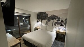 A bedroom with a bed, bedside tables, a desk, and a large window. - Mawün Hotel Pucón (Pucón)