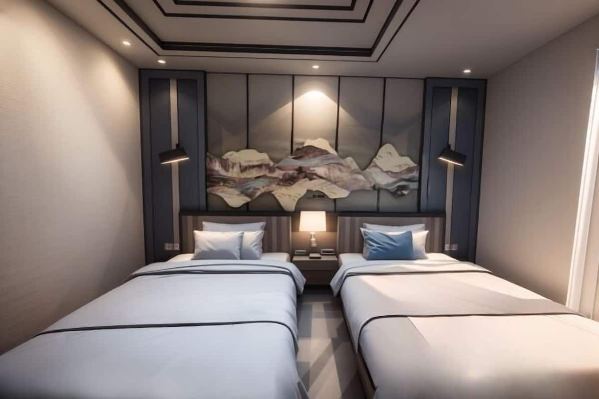 A modern hotel room with two beds, a large abstract painting on the wall, and a nightstand with a lamp.