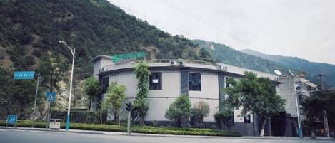 A building with a curved facade, a sign above the entrance, and a road in front with a traffic light.